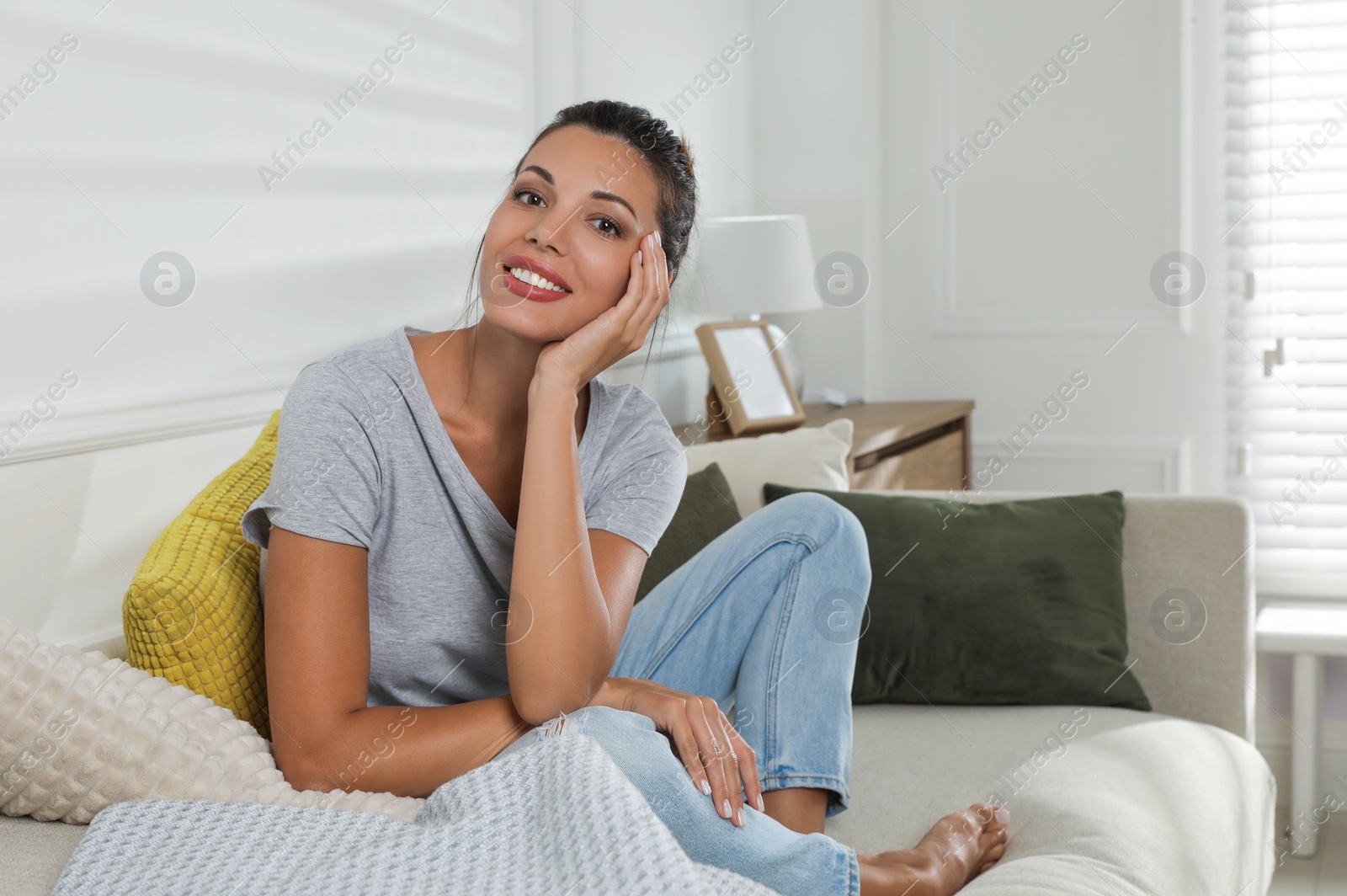 Photo of Beautiful woman sitting on sofa at home