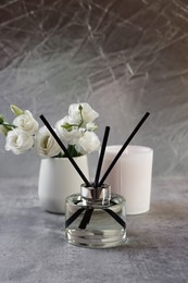 Reed diffuser, scented candle and eustoma flowers on gray marble table