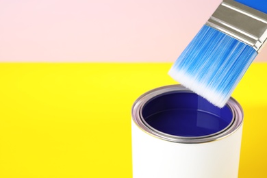 Photo of Open can of paint with brush on color background. Space for text