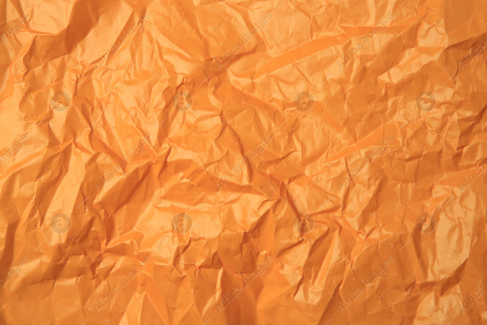 Photo of Sheet of crumpled orange paper as background, top view