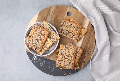 Photo of Cereal crackers with flax, sunflower and sesame seeds on grey table, top view