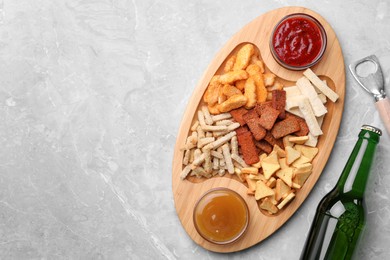 Photo of Different crispy rusks served with dip sauces and beer on light marble table, flat lay. Space for text