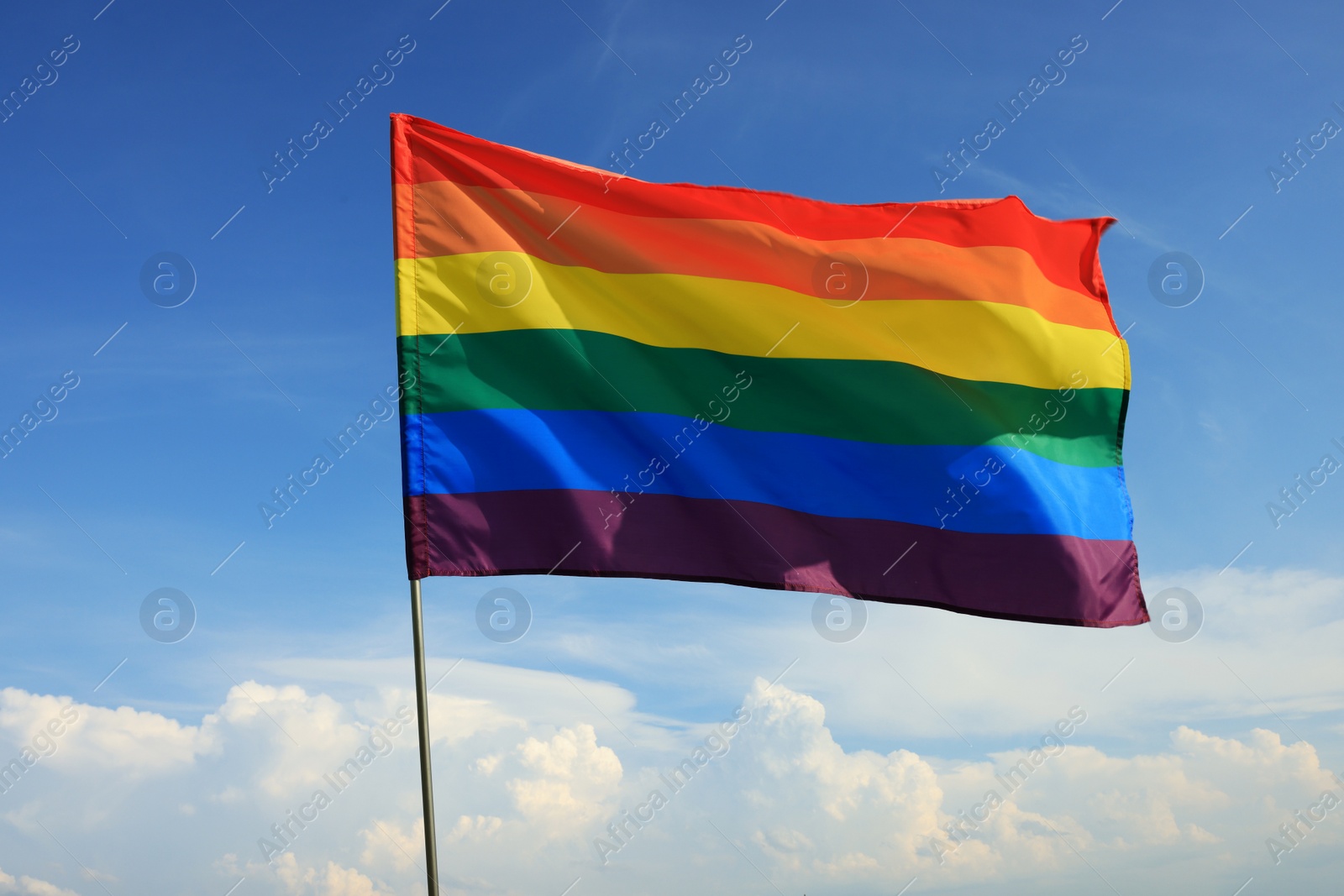 Photo of Bright LGBT flag fluttering against blue sky