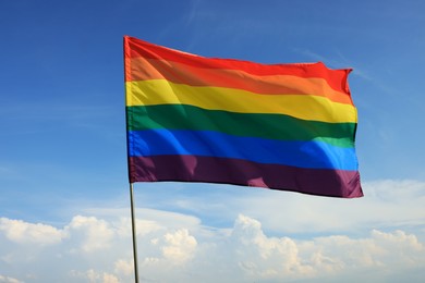 Photo of Bright LGBT flag fluttering against blue sky