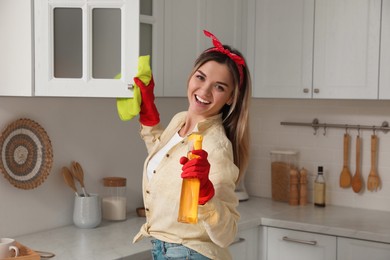 Photo of Woman with spray bottle and rag singing while cleaning at home