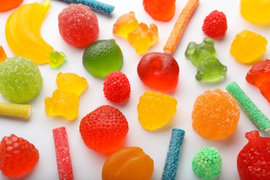 Mix of different delicious gummy candies on white background, flat lay