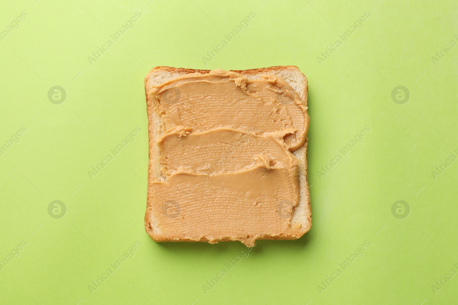 Photo of Tasty peanut butter sandwich on light green background, top view