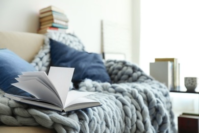 Open book on sofa in living room. Space for text