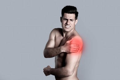 Image of Man suffering from shoulder pain on grey background