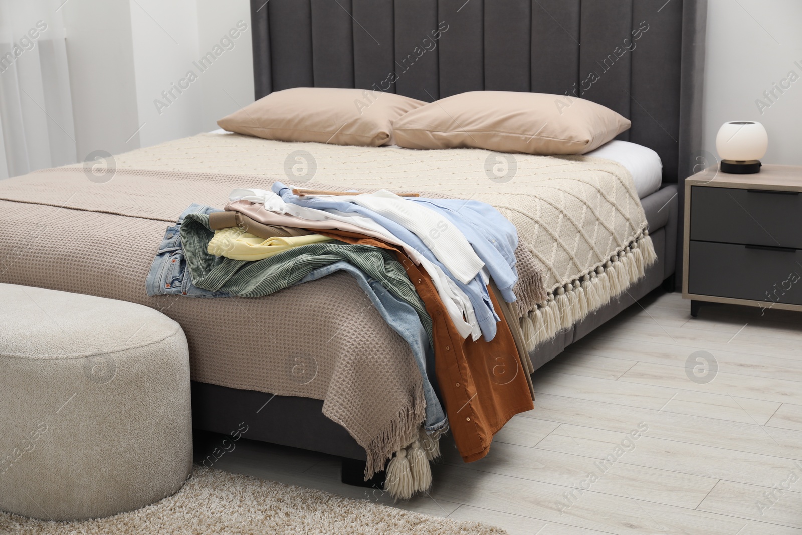 Photo of Pile of different clothes on bed at home