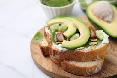 Tasty vegan sandwich with avocado, tomato and spinach on white marble table, closeup. Space for text