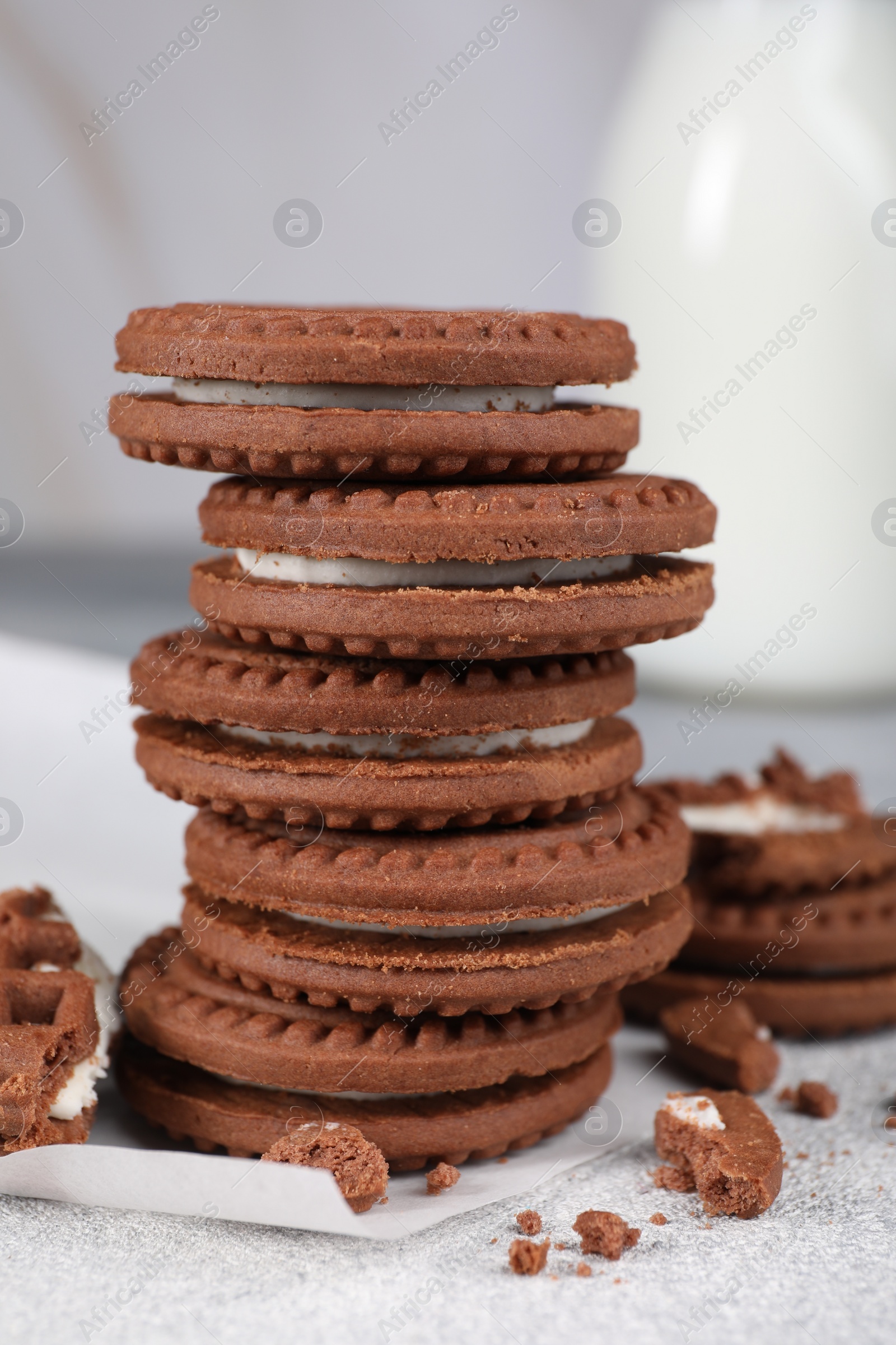 Photo of Tasty chocolate sandwich cookies with cream on light grey table, closeup