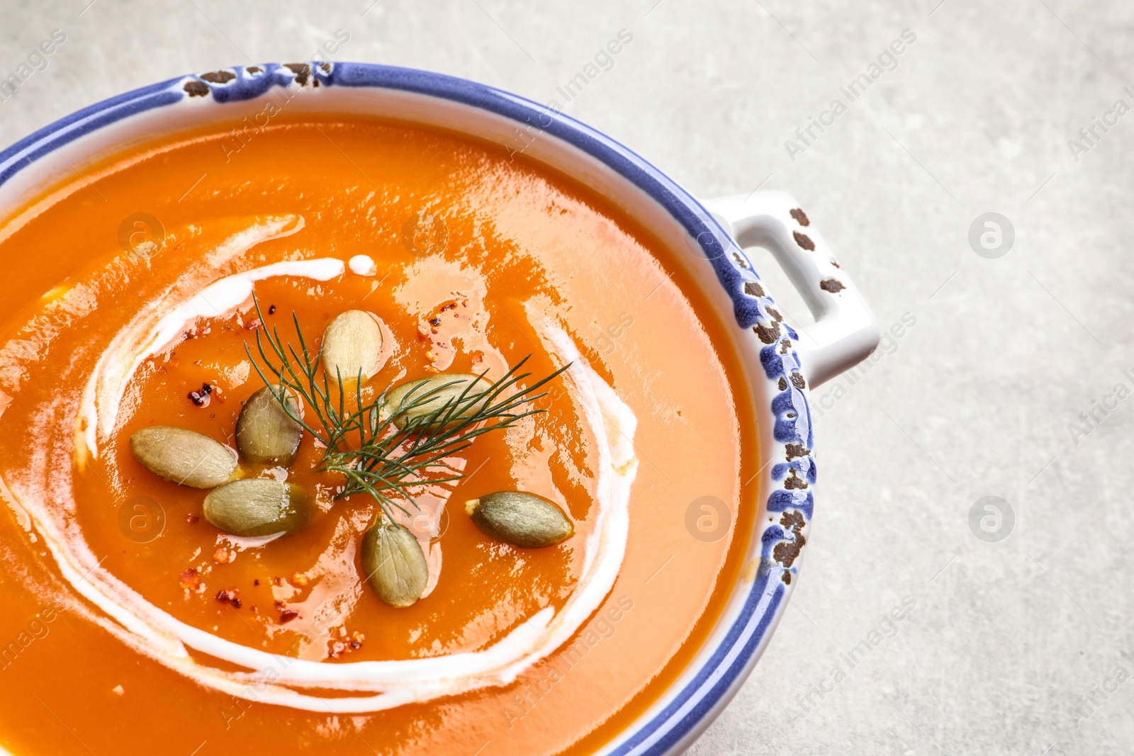 Photo of Bowl of tasty sweet potato soup on table, closeup. Space for text