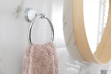 Photo of Holder with clean towel on light wall in bathroom