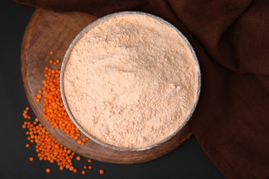 Photo of Bowl of lentil flour and seeds on dark table, top view