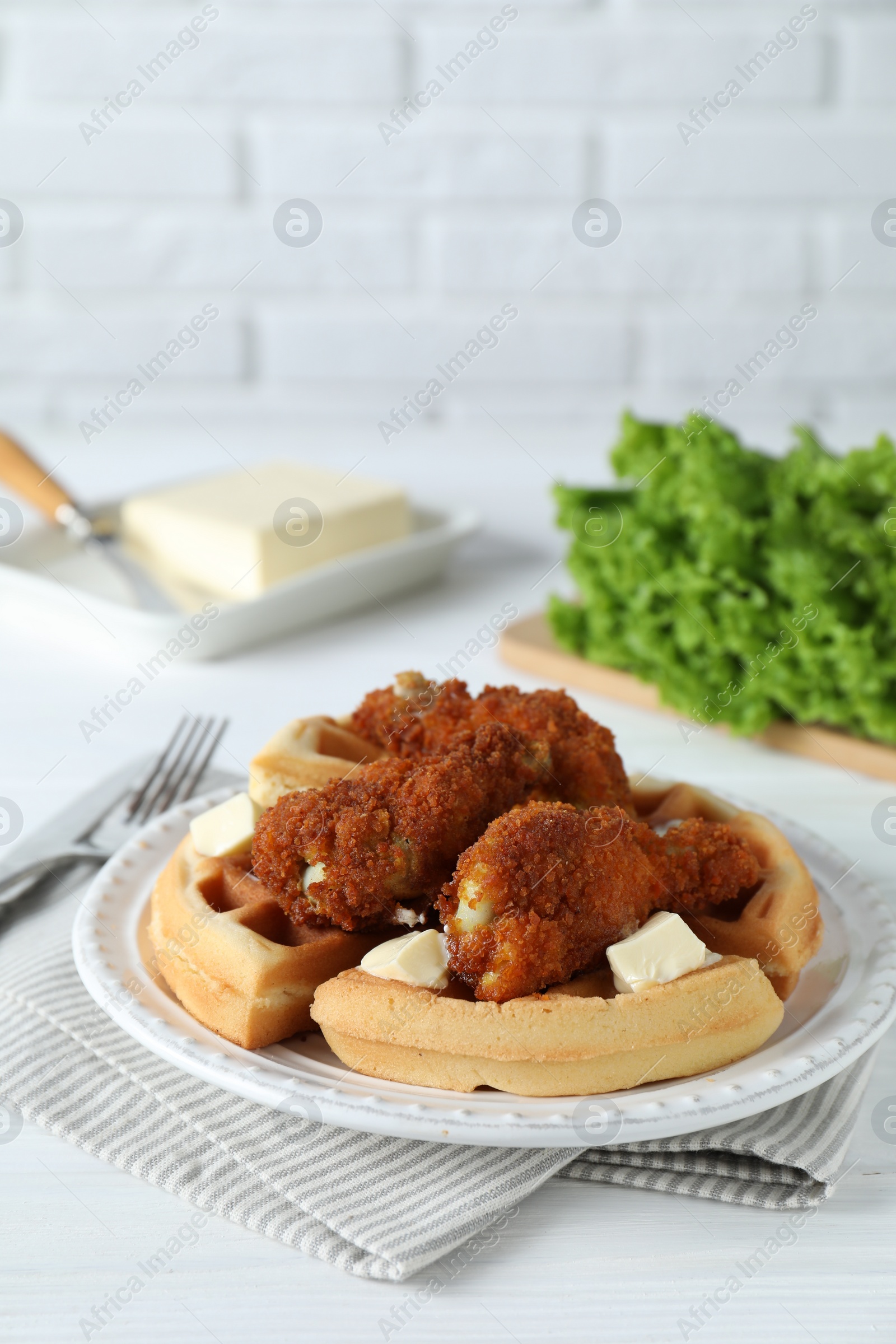 Photo of Delicious Belgium waffles served with fried chicken and butter on white table, space for text