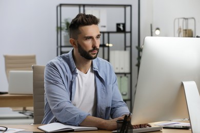 Photo of Man working on computer at table in office