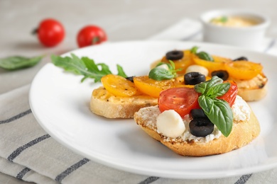 Photo of Plate of delicious tomato bruschettas on table, closeup