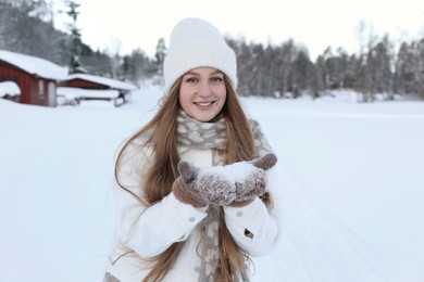 Photo of Winter vacation. Beautiful woman holding pile of snow outdoors