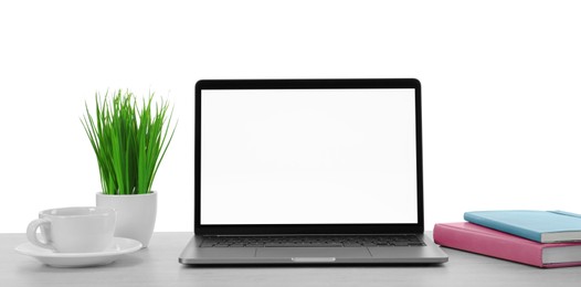 Photo of Laptop, potted plant and notebooks on table against white background. Stylish workplace