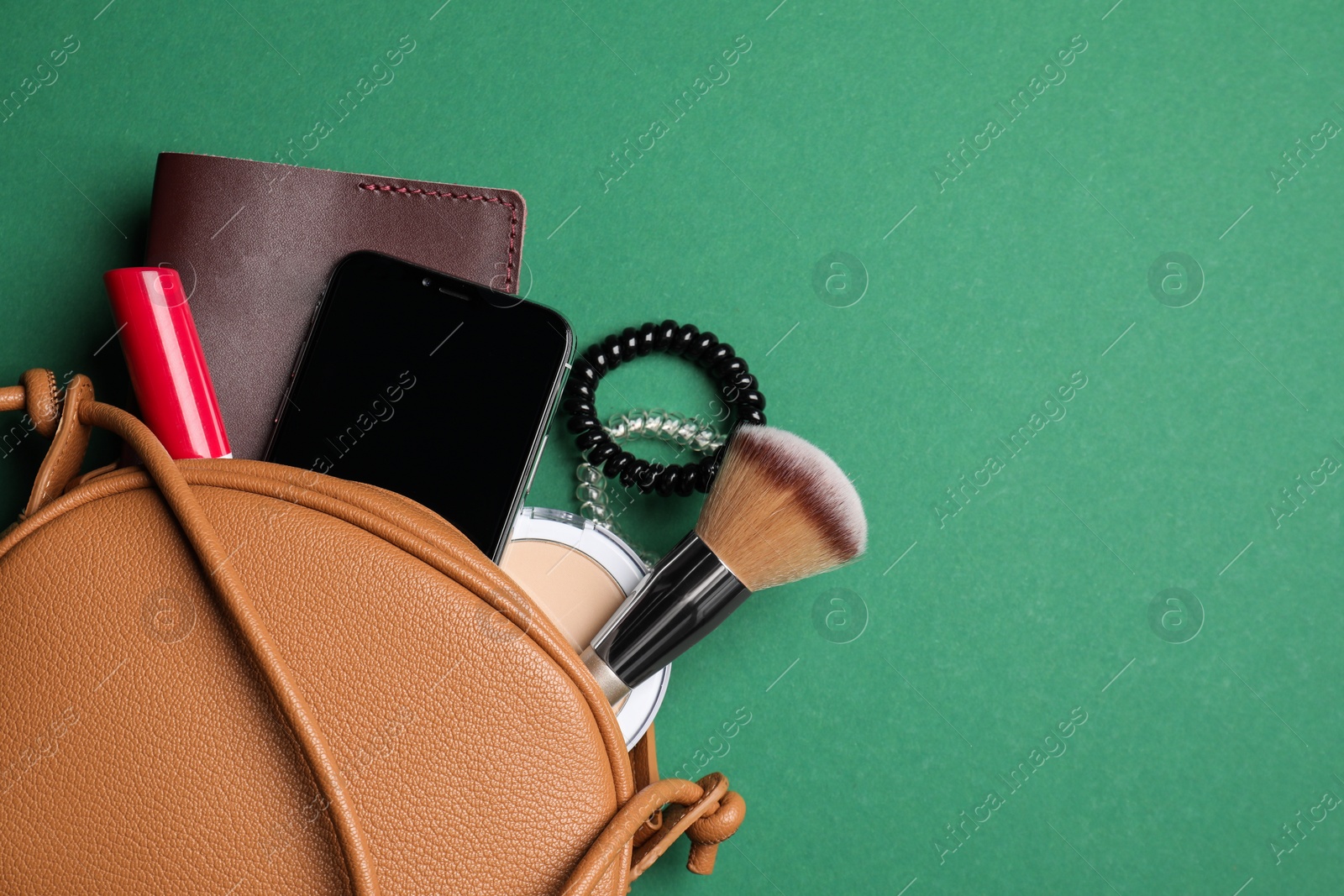 Photo of Stylish woman's bag with smartphone and accessories on green background, flat lay. Space for text