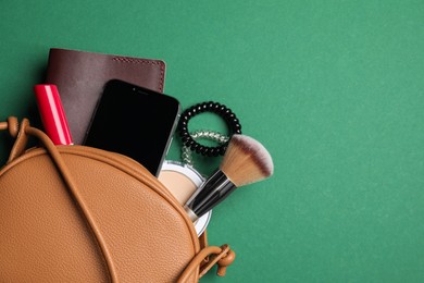 Photo of Stylish woman's bag with smartphone and accessories on green background, flat lay. Space for text
