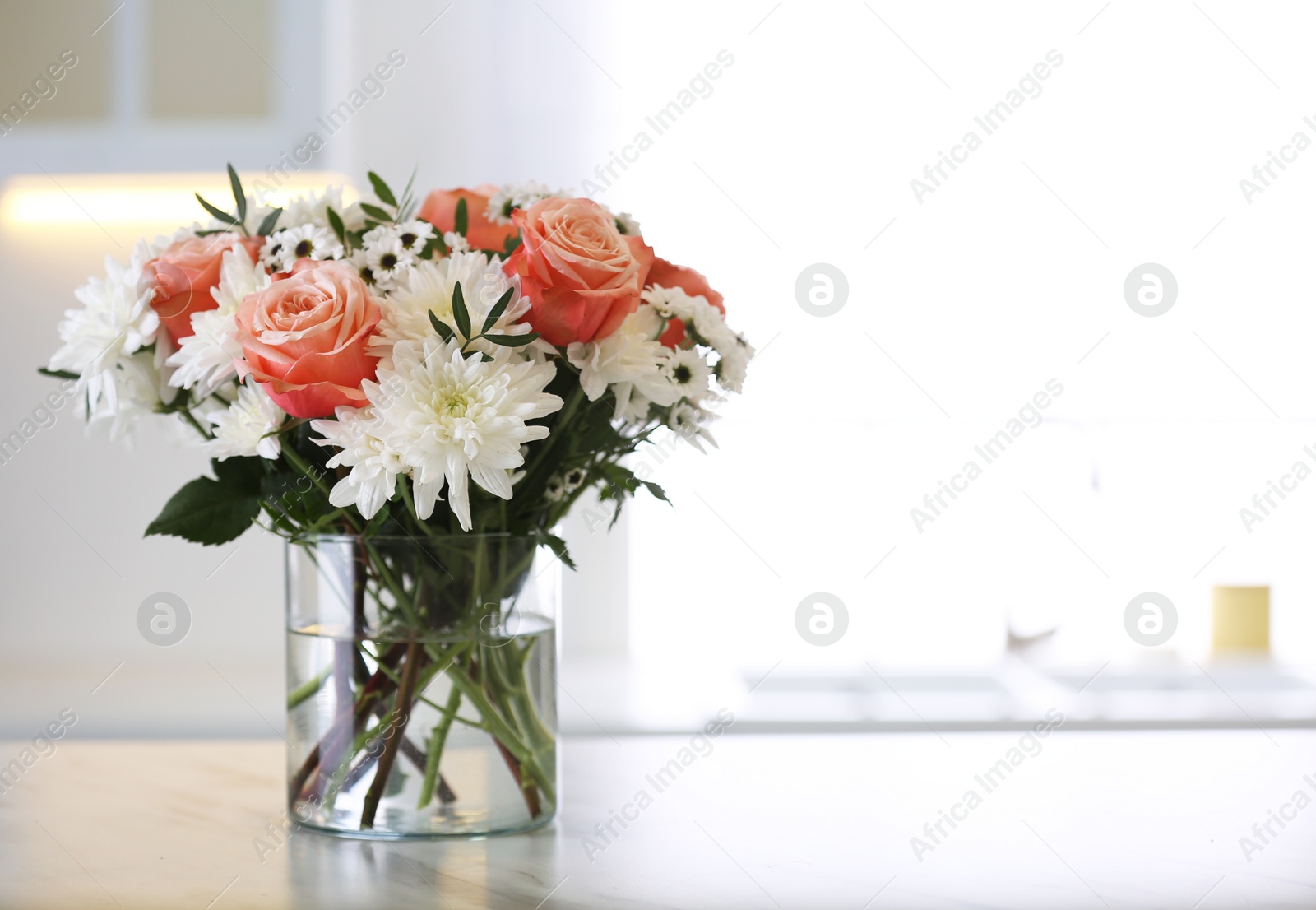 Photo of Vase with beautiful flowers on table in kitchen, space for text. Interior design