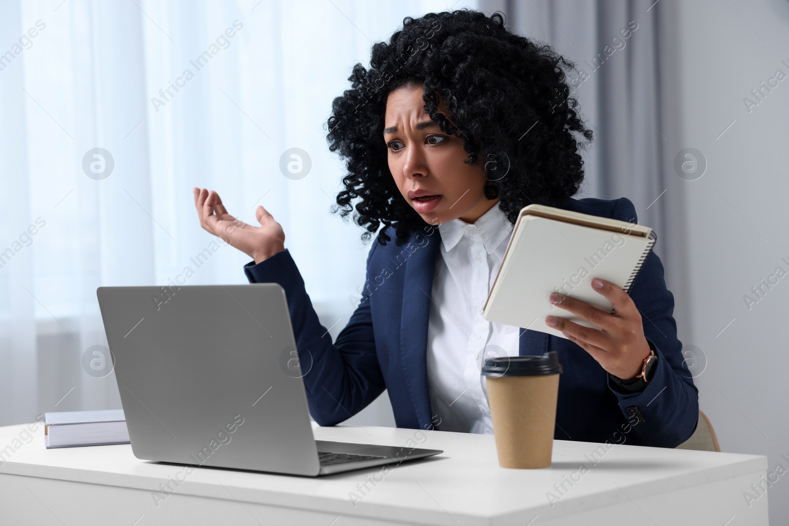 Photo of Deadline concept. Emotional woman looking at laptop and holding notepad in office