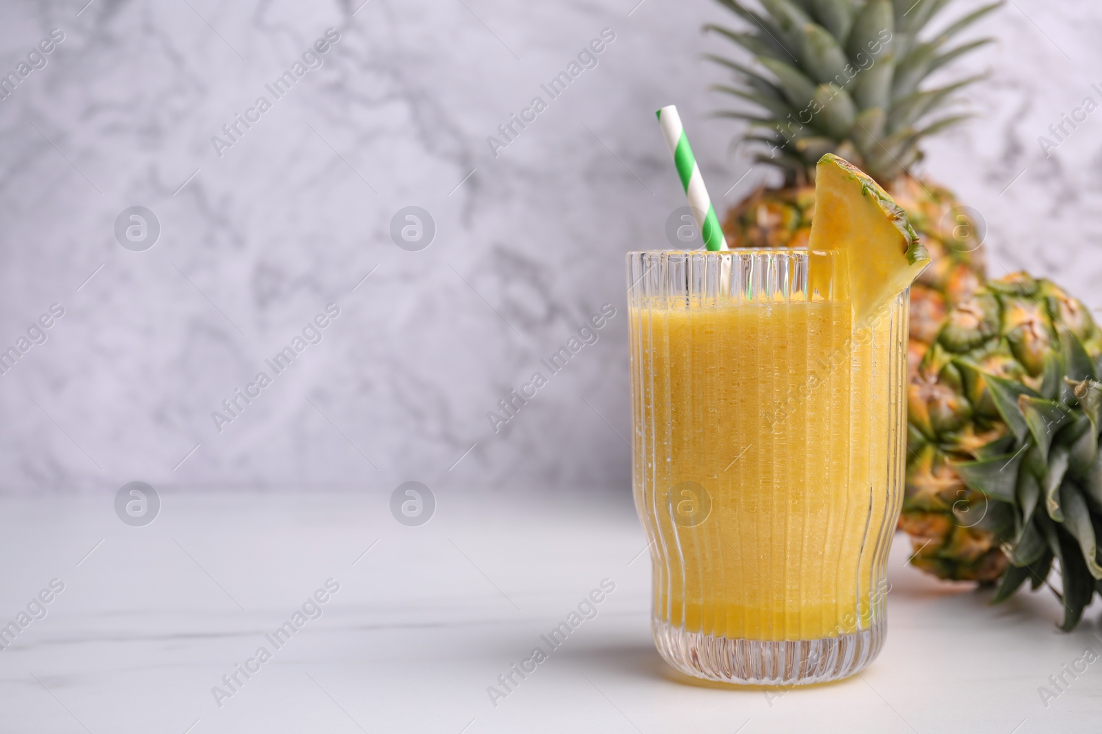 Photo of Tasty pineapple smoothie and fresh fruits on white table, space for text