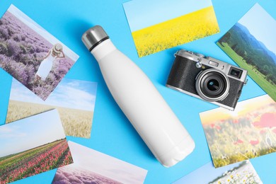 Stylish thermo bottle, camera and different photos on light blue background, flat lay