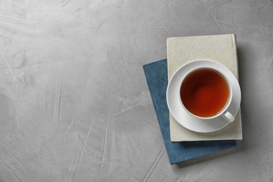 Photo of Hardcover books and cup of tea on grey stone background, top view. Space for text