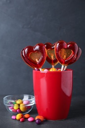Photo of Delicious heart shaped lollipops and dragees on black table
