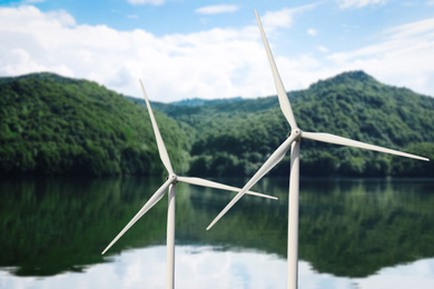 Image of Alternative energy source. Wind turbines near mountains