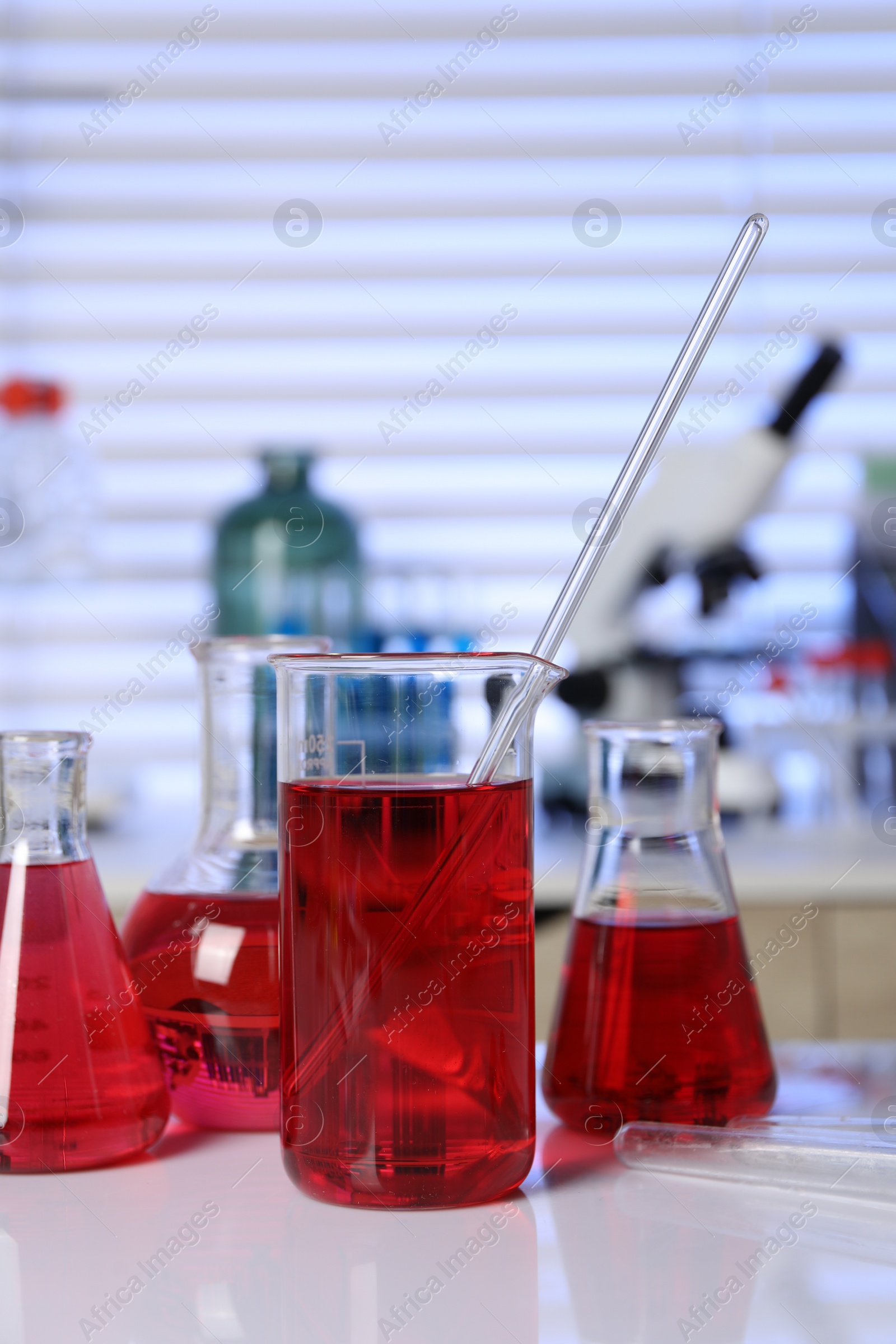 Photo of Laboratory analysis. Different glassware with red liquid on white table indoors