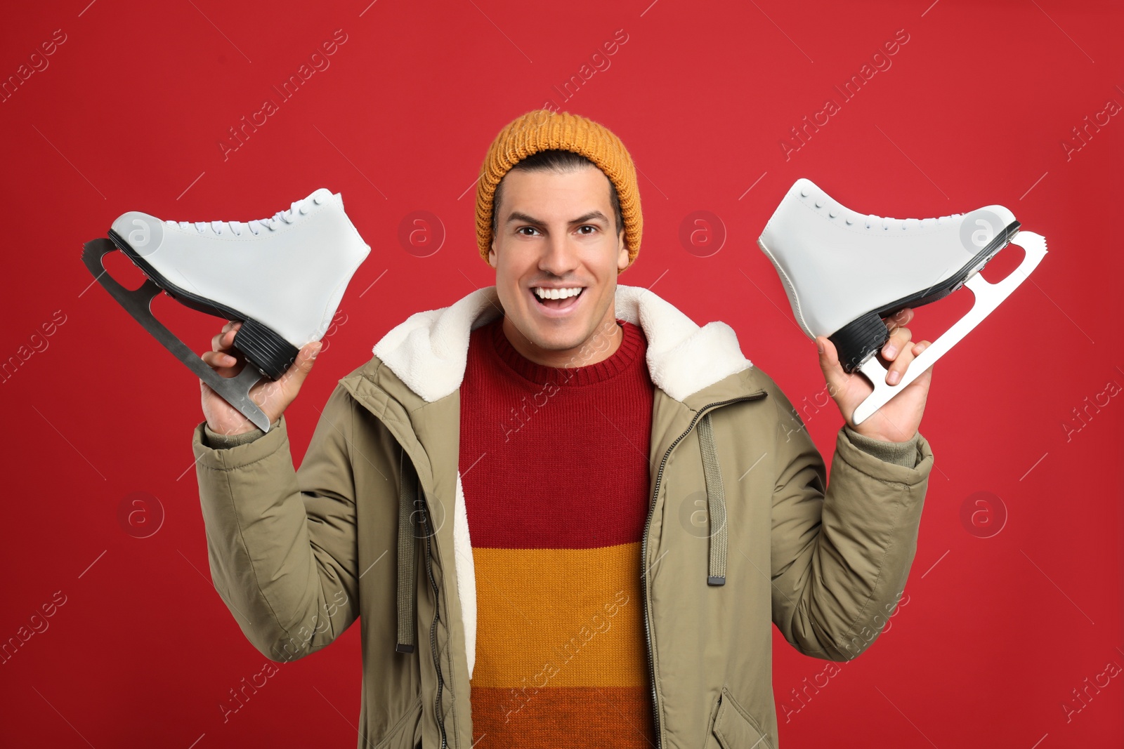 Photo of Emotional man with ice skates on red background