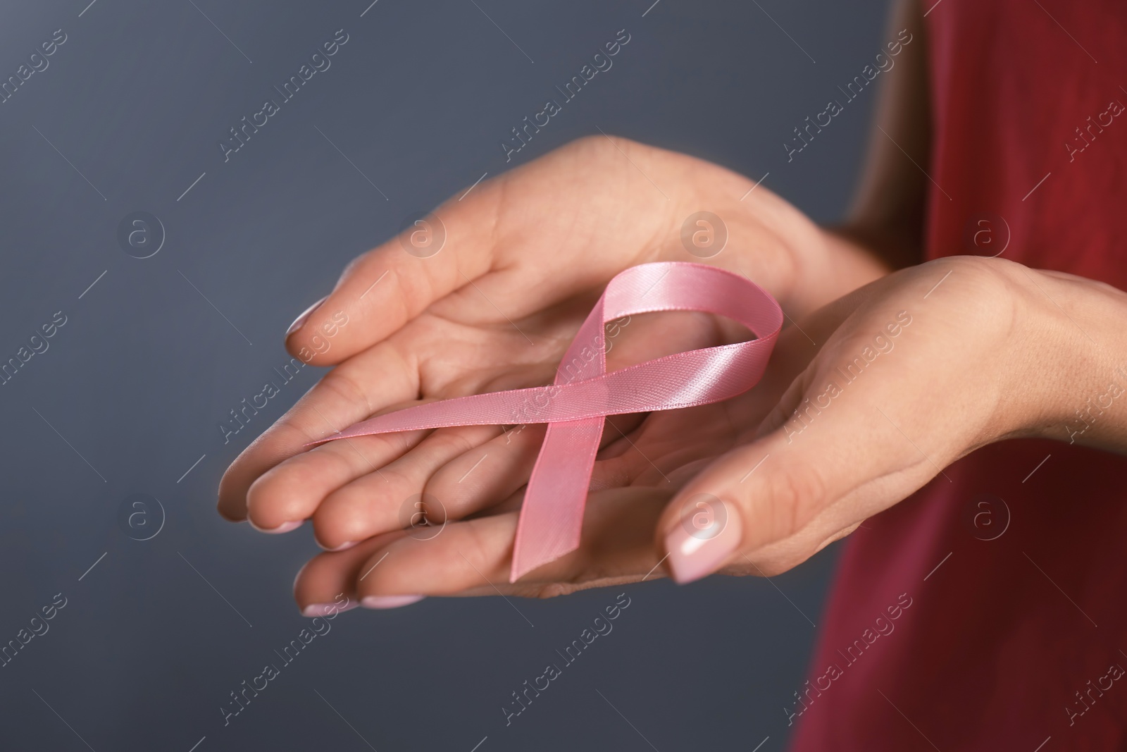 Photo of Woman holding pink ribbon on grey background, closeup. Breast cancer awareness