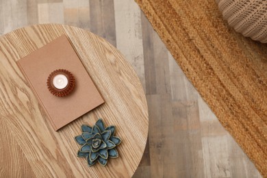 Photo of Book, candle and decor on round wooden table indoors, top view