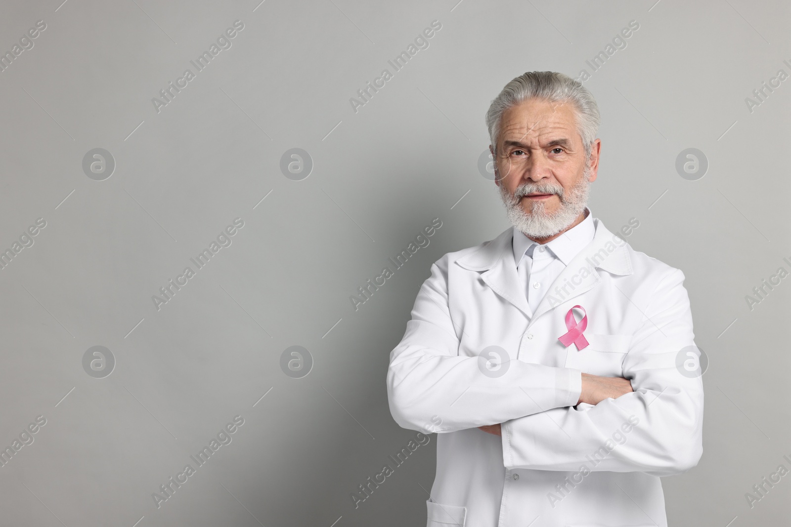 Photo of Mammologist with pink ribbon on gray background, space for text. Breast cancer awareness