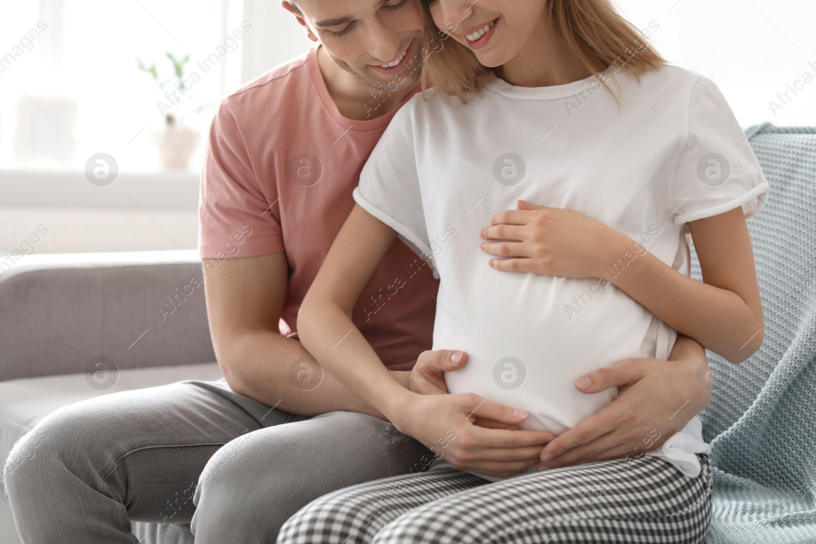 Photo of Young pregnant woman with her husband at home