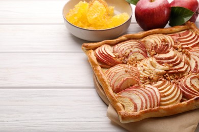 Photo of Tasty fresh apple galette and ingredients on white wooden table, closeup. Space for text