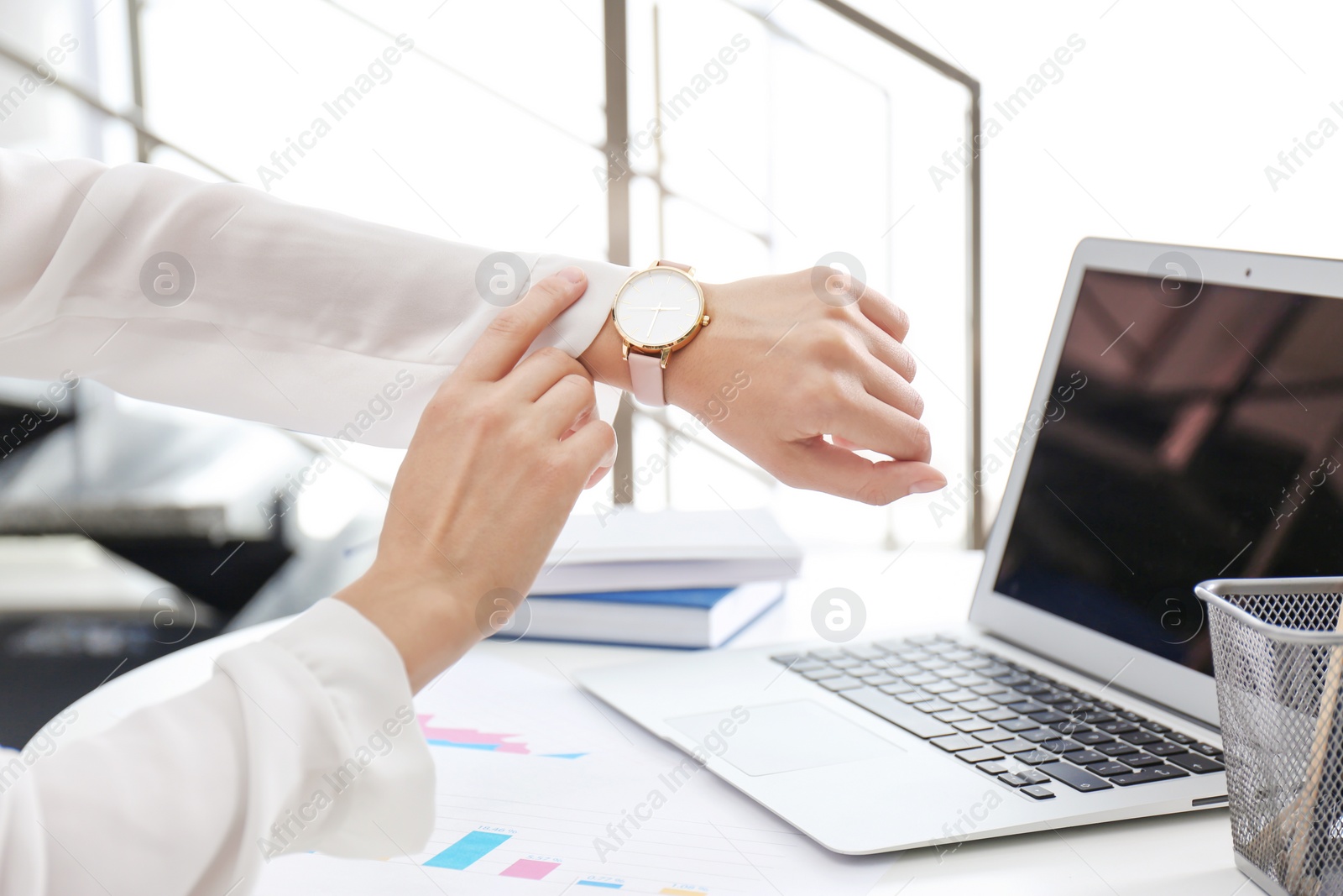 Photo of Young businesswoman checking time on her wristwatch at workplace. Time management