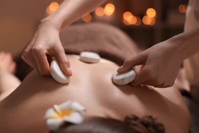 Photo of Spa therapy. Beautiful young woman lying on table during hot stone massage in salon, closeup