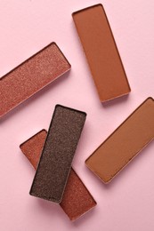 Different beautiful eye shadows on pink background, flat lay