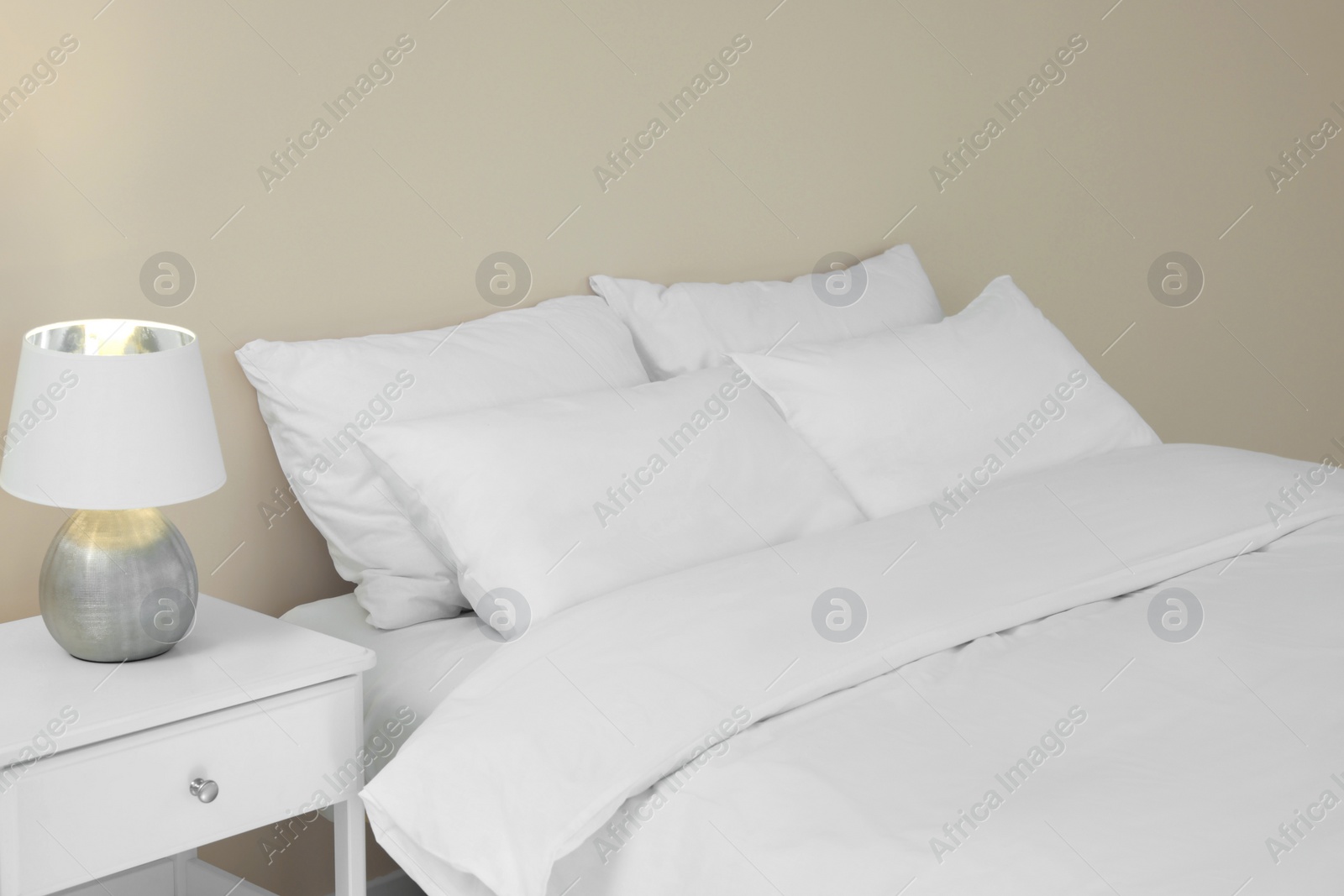 Photo of White soft pillows on cozy bed in room