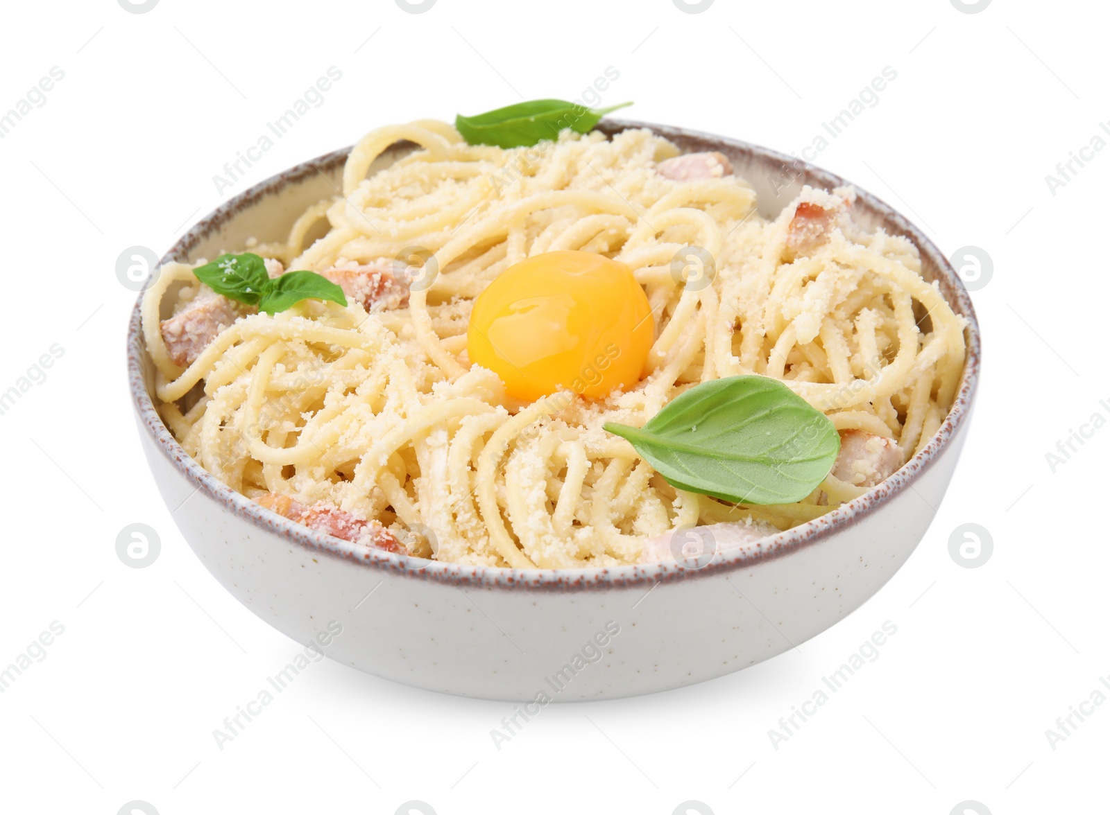 Photo of Bowl of tasty pasta Carbonara with basil leaves and egg yolk isolated on white