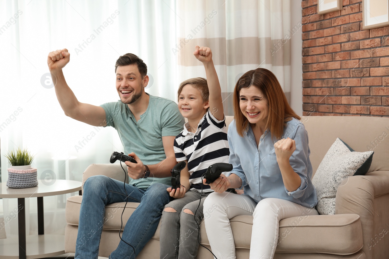 Photo of Happy family playing video games on sofa in living room