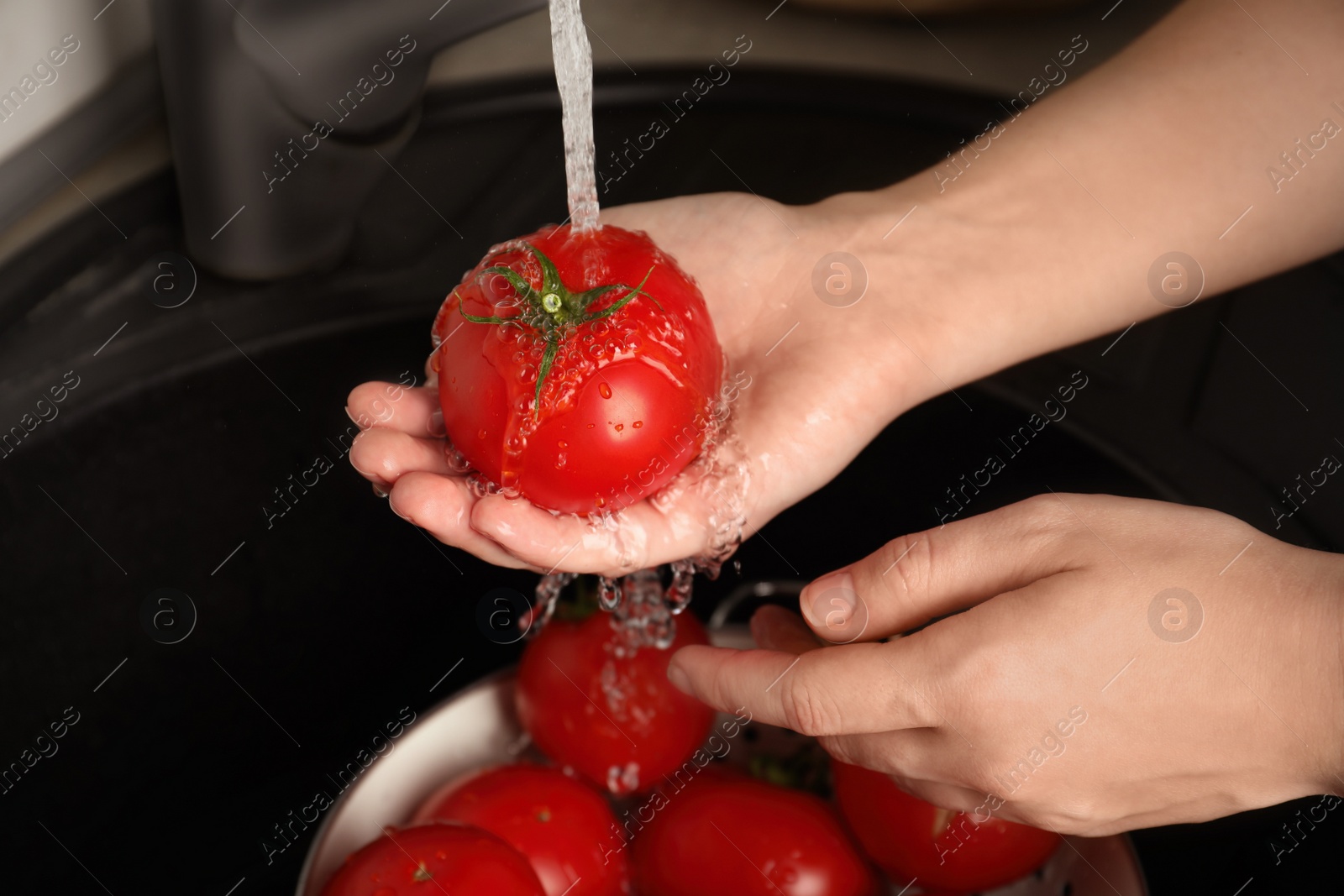 Photo of Woman washing ripe tomatoes in sink, closeup