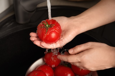 Photo of Woman washing ripe tomatoes in sink, closeup