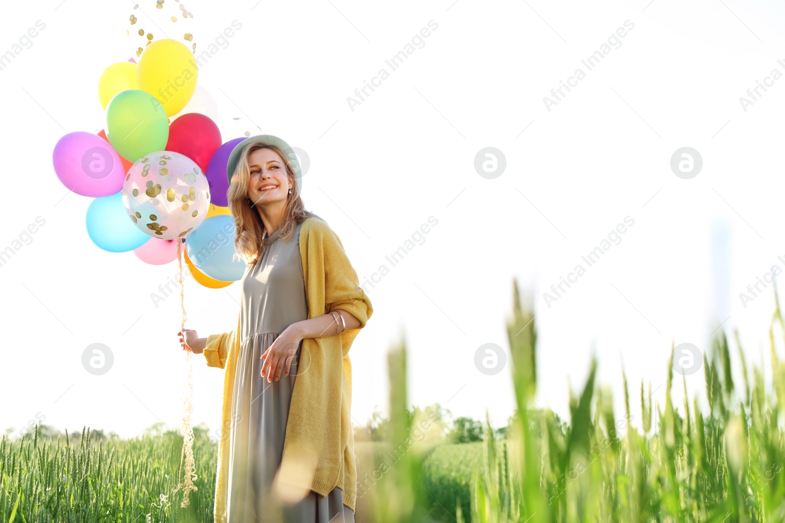 Photo of Young woman with colorful balloons outdoors on sunny day