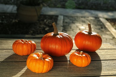 Photo of Many whole ripe pumpkins on wooden table outdoors